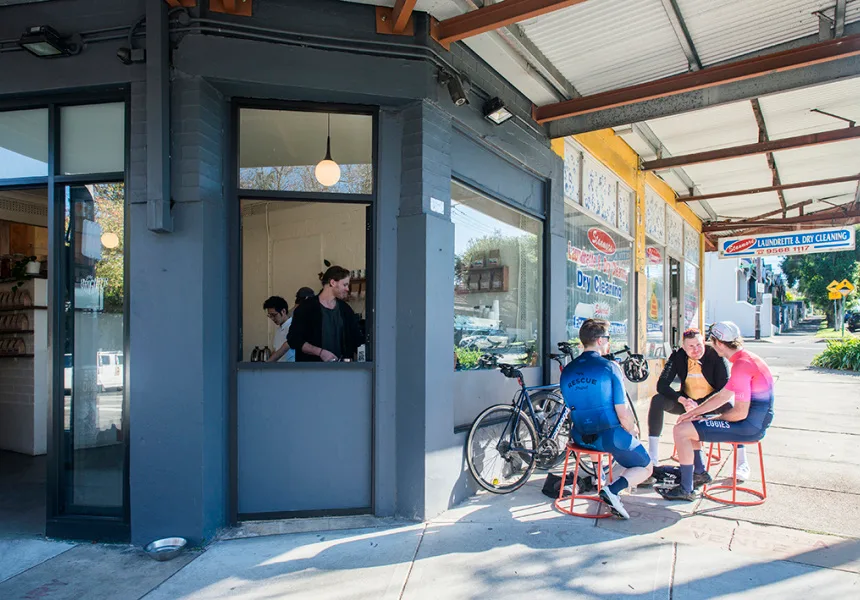small blue café with customers seated outside on red stools near bicycle., brighter coffee, stanmore