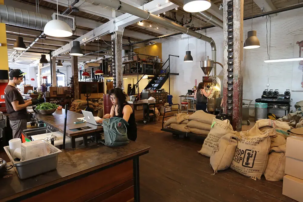 industrial coffee roastery workspace with burlap bags, roasting equipment, and working staff., brooklyn roasting company, bro