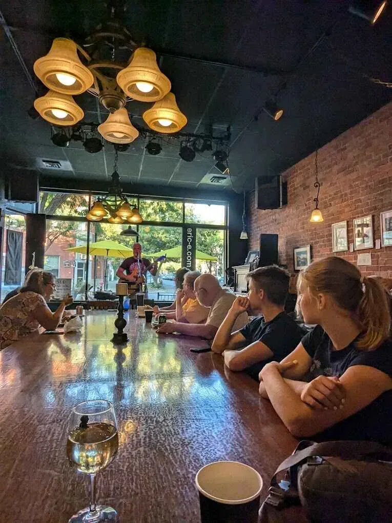 group gathered at bar counter watching musician perform indoors., bucer's coffee house pub, idaho