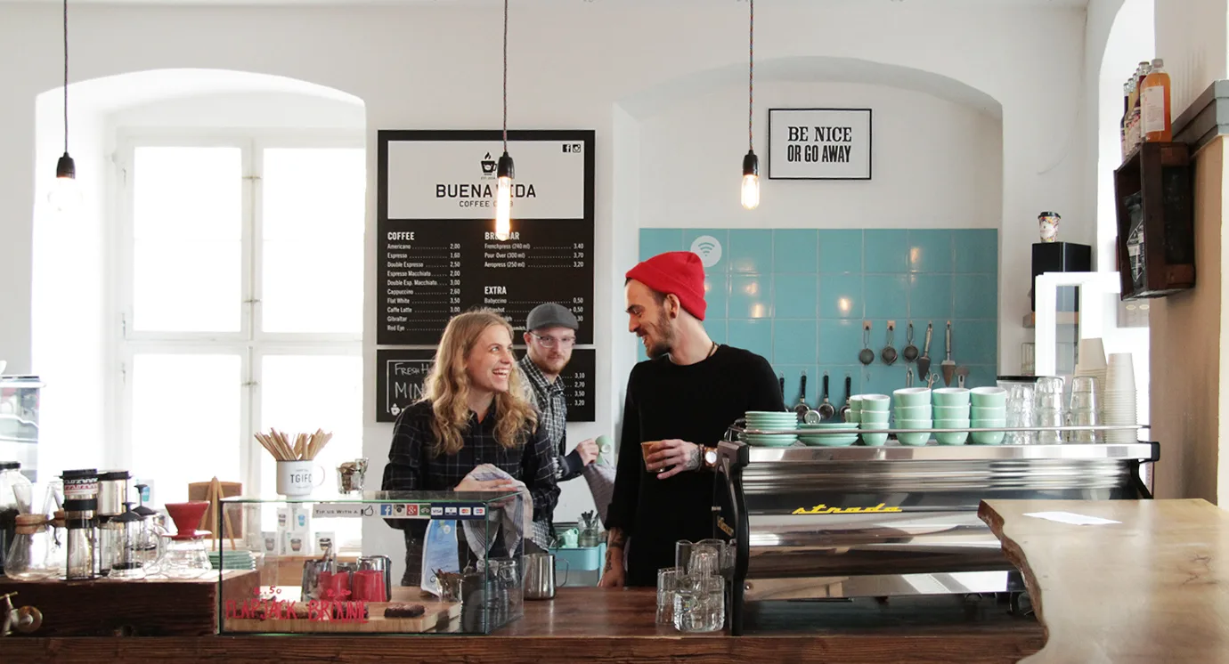 coffee shop interior with staff behind counter, menu board, and "be nice or go away" sign., buena vida coffee roasters, potsd