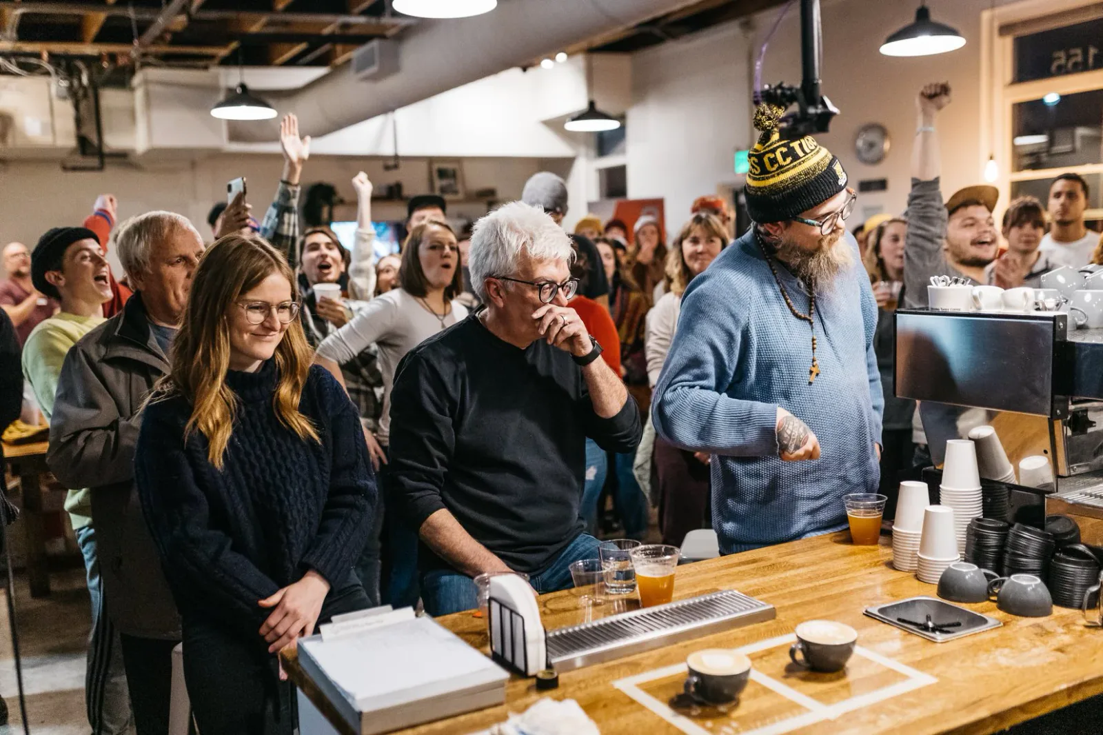 large crowd gathered in industrial space watching event at wooden counter bar., building 3 coffee, colorado springs