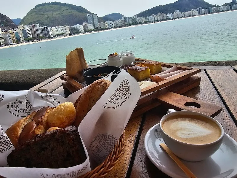 beachfront breakfast spread with pastries, coffee, and turquoise bay view., café 18 do forte, rio de janeiro