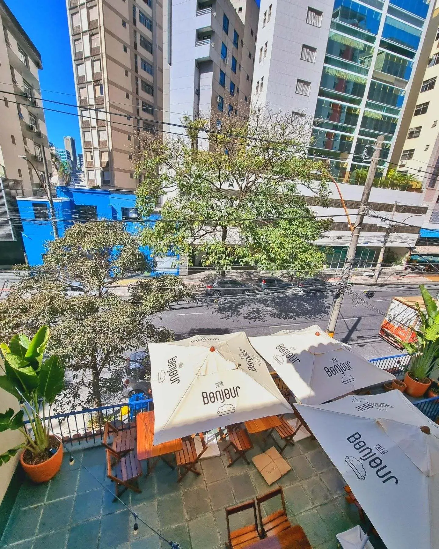 outdoor café terrace with umbrellas overlooking urban street and buildings., café bonjour, belo horizonte