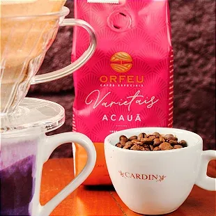 pink acaua coffee bag with white mugs containing coffee and cocoa beans on orange surface., café cardin, rio de janeiro