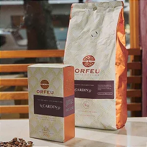 orfeu coffee packaging displayed with beans scattered on white surface., café cardin, rio de janeiro