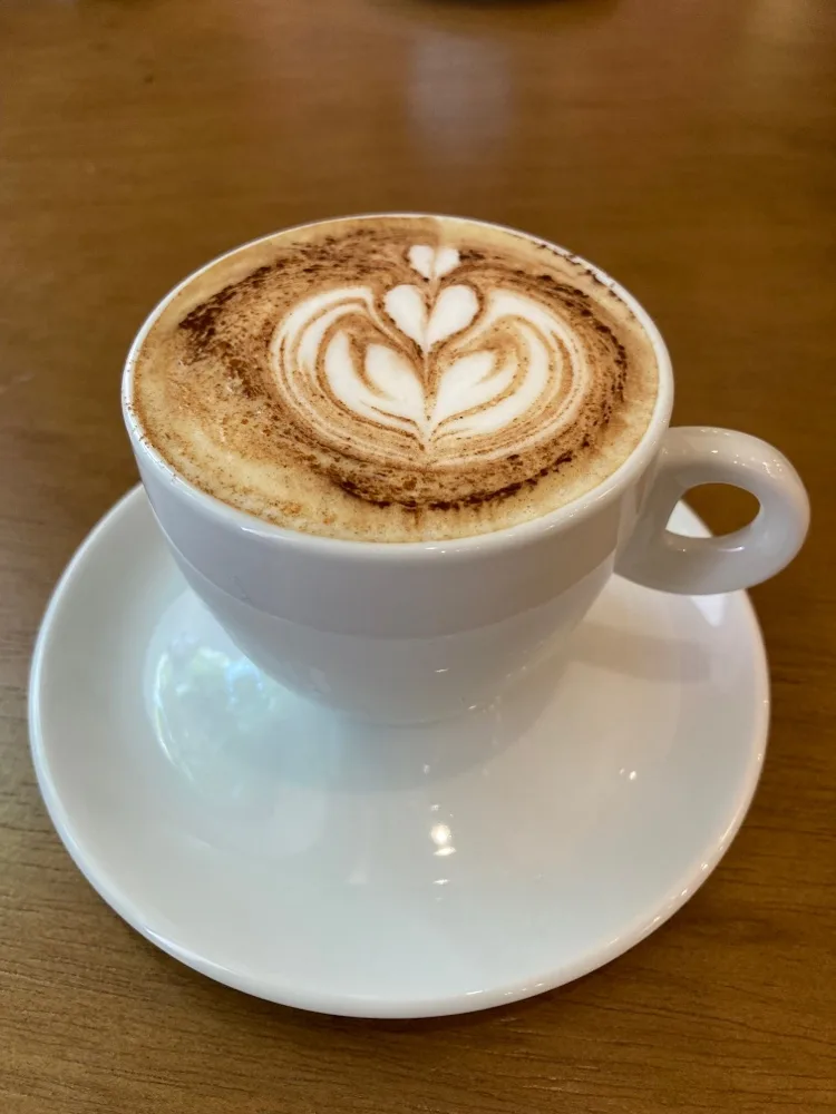 latte with heart-shaped latte art in white cup on wooden table., café da carol, rio de janeiro