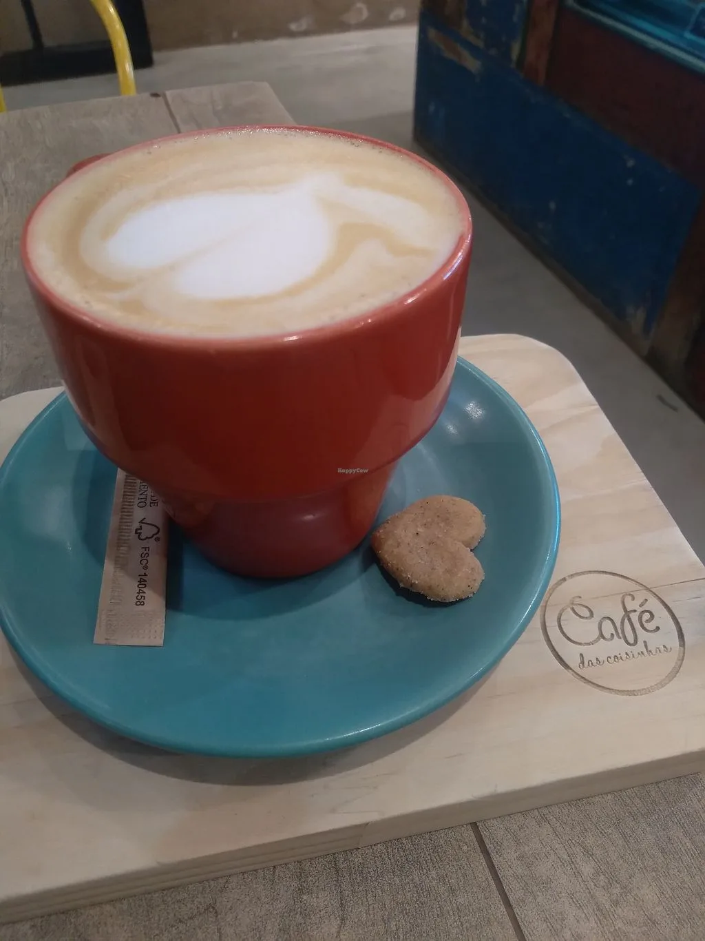 red cup with latte art on turquoise saucer, heart-shaped cookie, café stamp., café das coisinhas, são paulo
