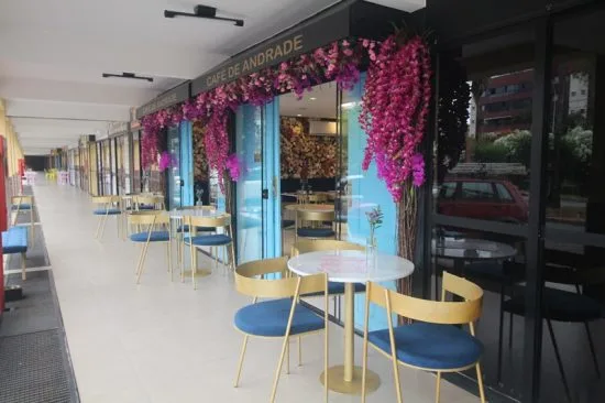 modern café with vibrant pink floral display and contemporary seating arrangement., café de andrade - cafeteria no sudoeste, 
