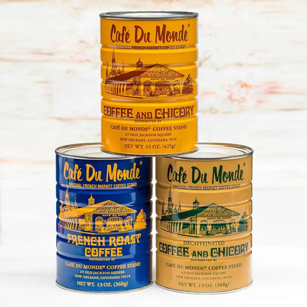 three stacked café du monde coffee cans in yellow, blue, and tan varieties., cafe du monde, new orleans