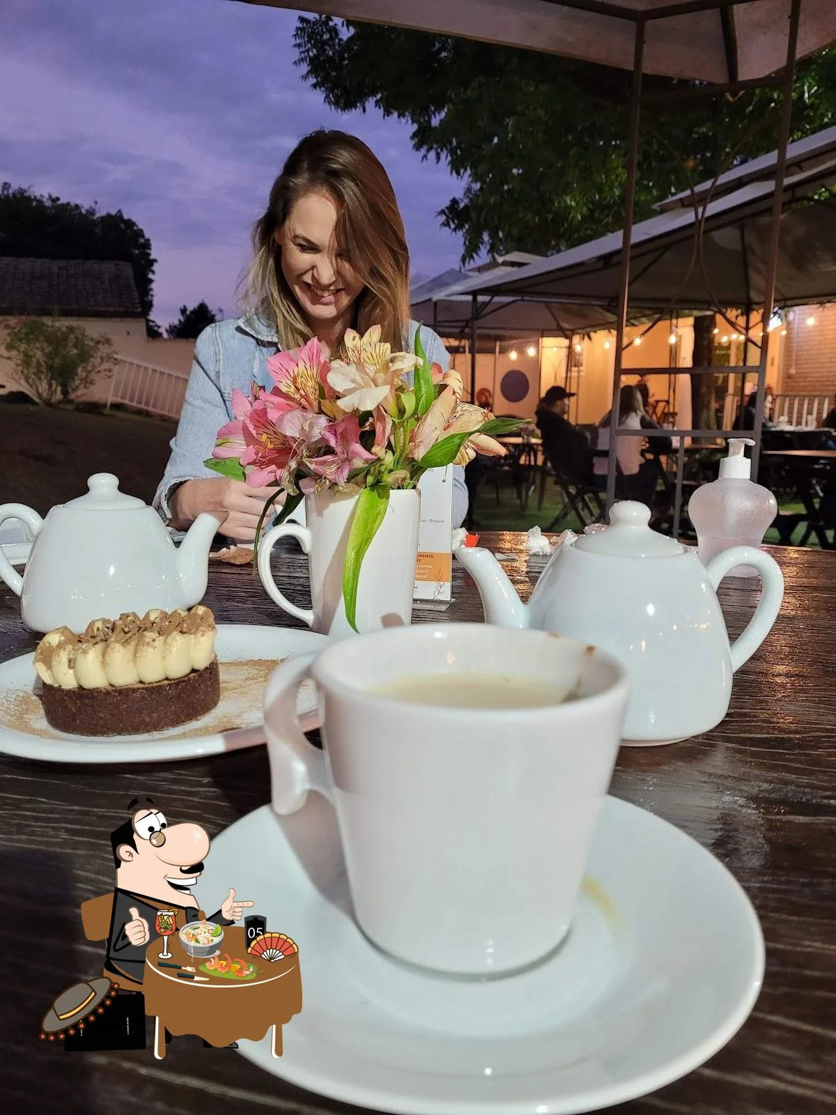 woman arranging pink and white flowers at outdoor evening tea service table., café flor de laranjeira, curitiba