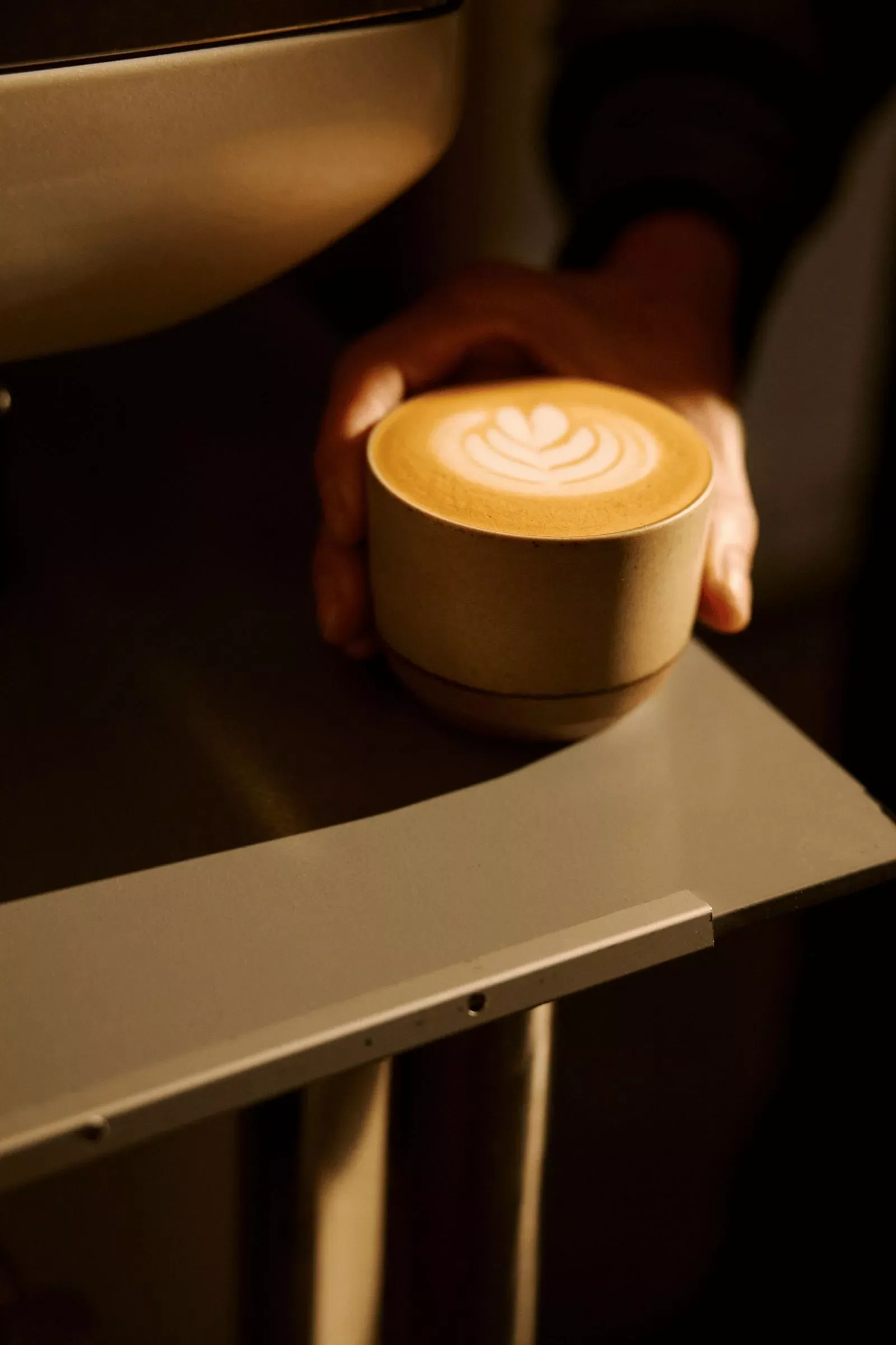 hand holding creamy cappuccino with latte art on wooden table., café guayacán, madrid