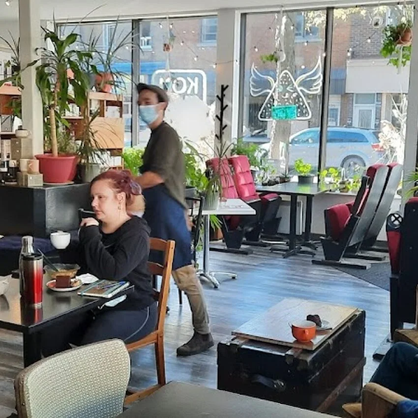 modern office space with plants, two people, large windows, and casual seating areas., café komma rosta, verdun