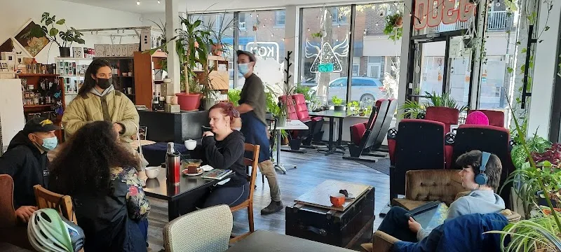 community space with diverse group of people, plants, and casual seating areas., café komma rosta, verdun