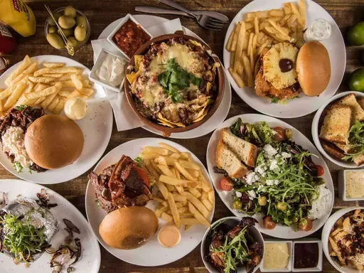 overhead view of restaurant table with burgers, fries, salads, and appetizers served on white plates., café løkka, trondheim