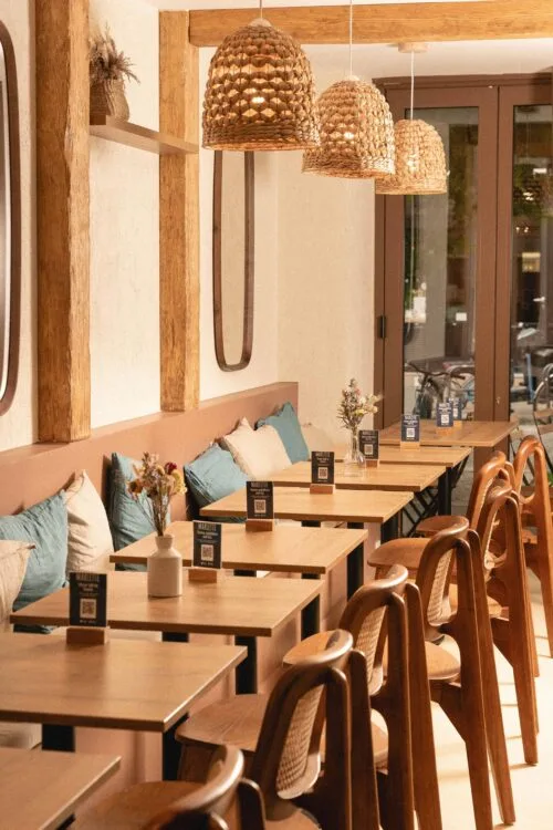 modern café with wooden tables, rattan pendant lights, and blue cushioned seating., café marlette - brunch montmartre, paris
