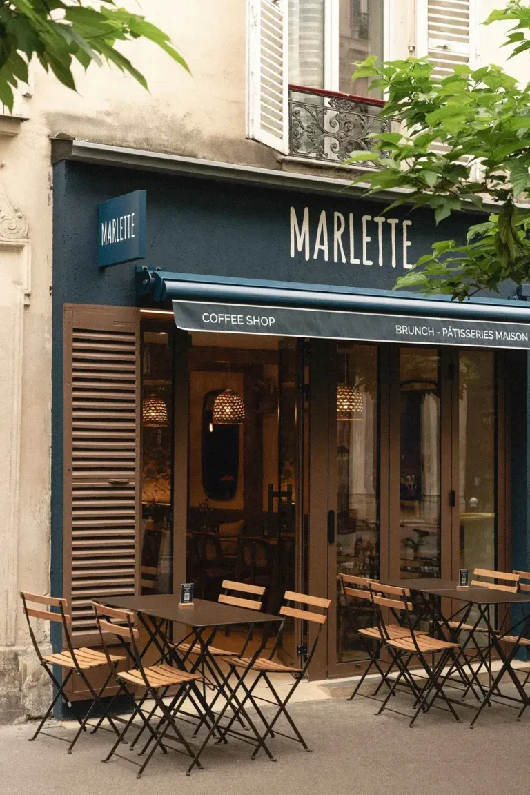 marlette coffee shop storefront with outdoor seating and green foliage overhead., café marlette - brunch pigalle, paris