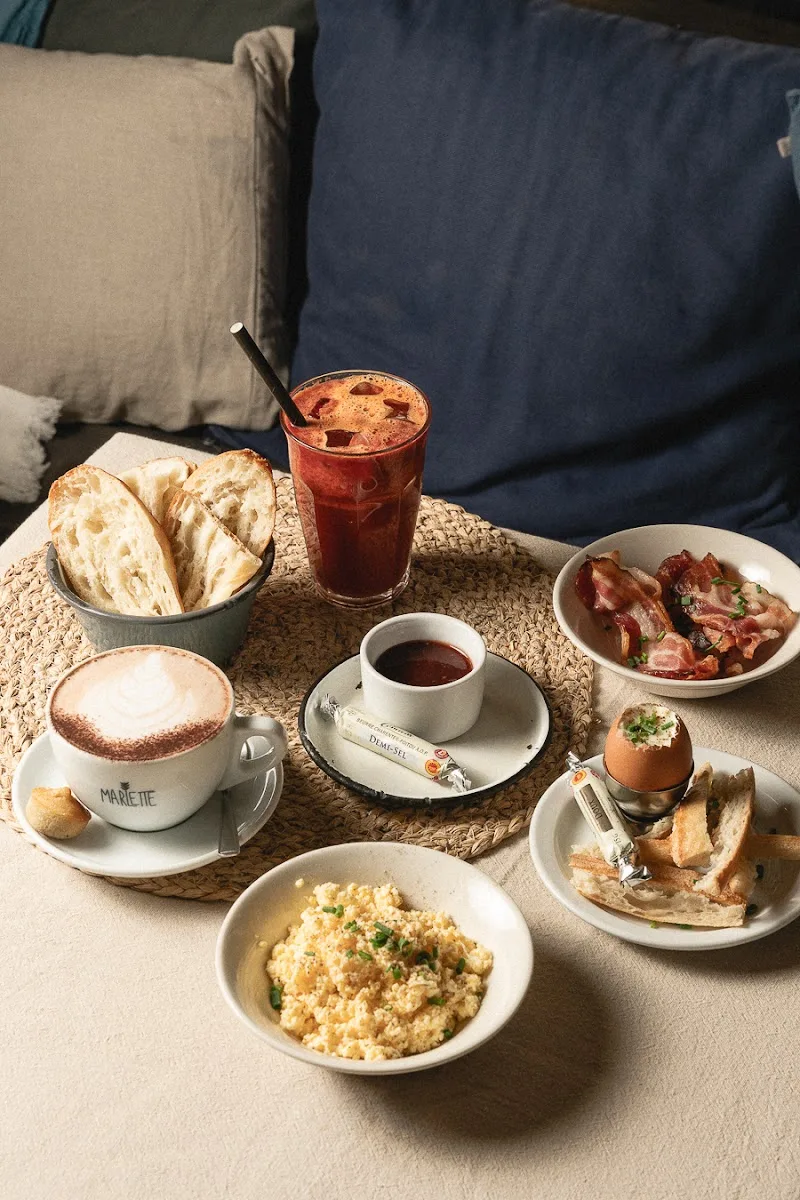 breakfast spread with coffee, scrambled eggs, bacon, bread, and boiled egg on table., café marlette - brunch pigalle, paris