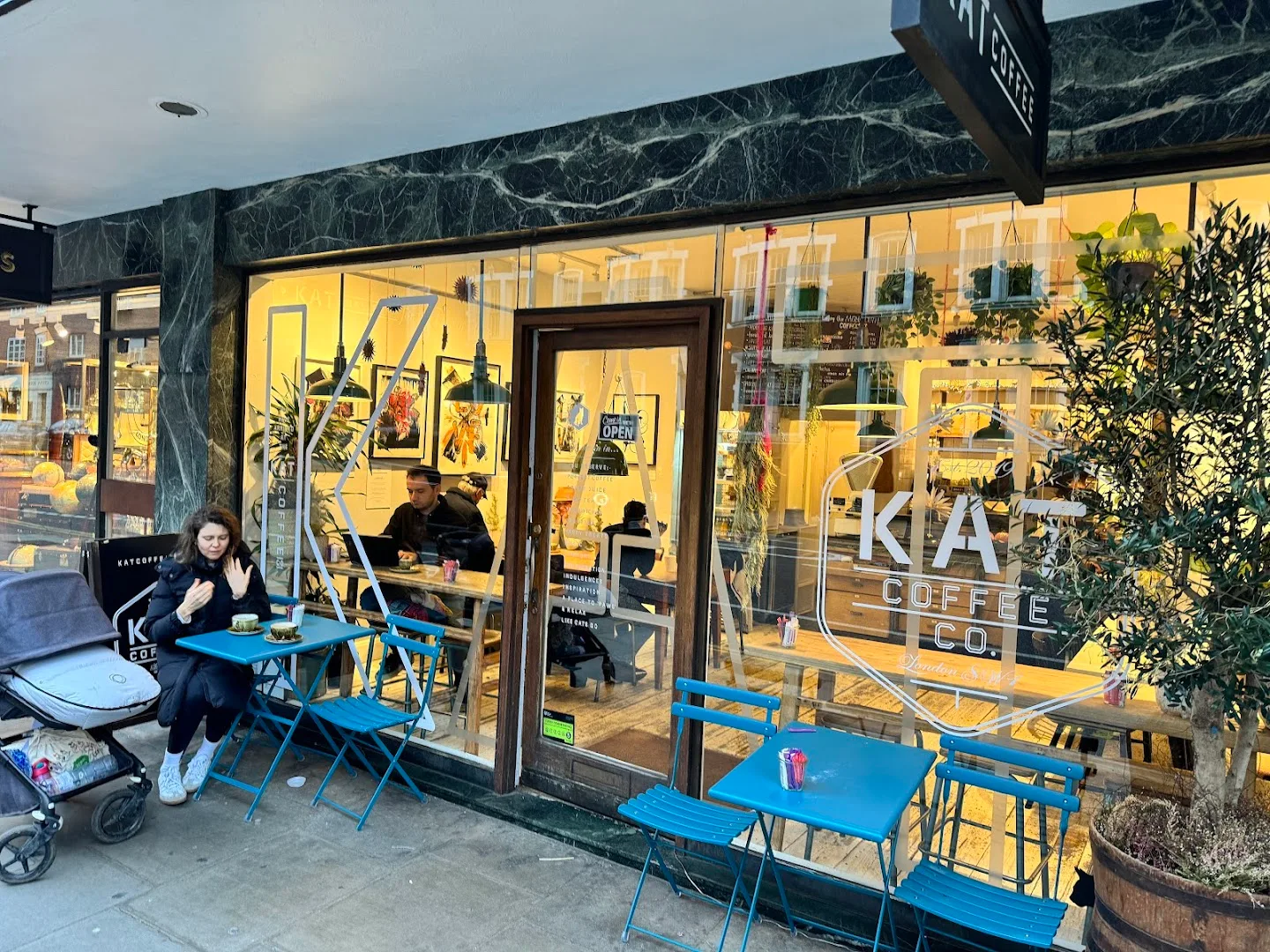 kia coffee co. storefront with blue outdoor seating and warm interior lighting., cafe nos: specialty coffee & craft bakery, b
