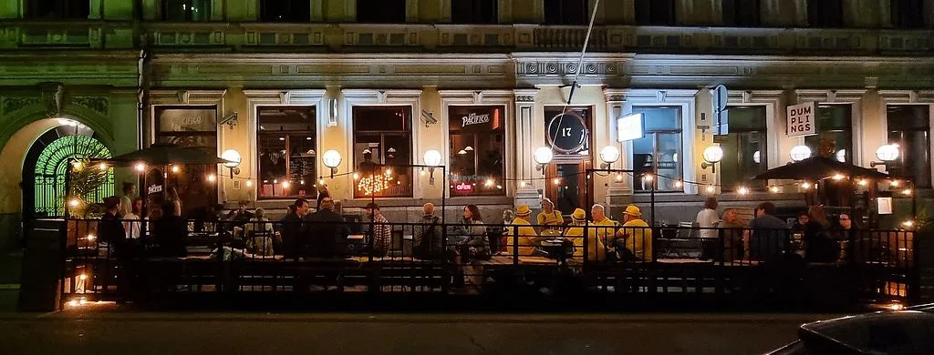crowded outdoor bar terrace at night with warm lighting and seated patrons., cafe pacifico, helsinki