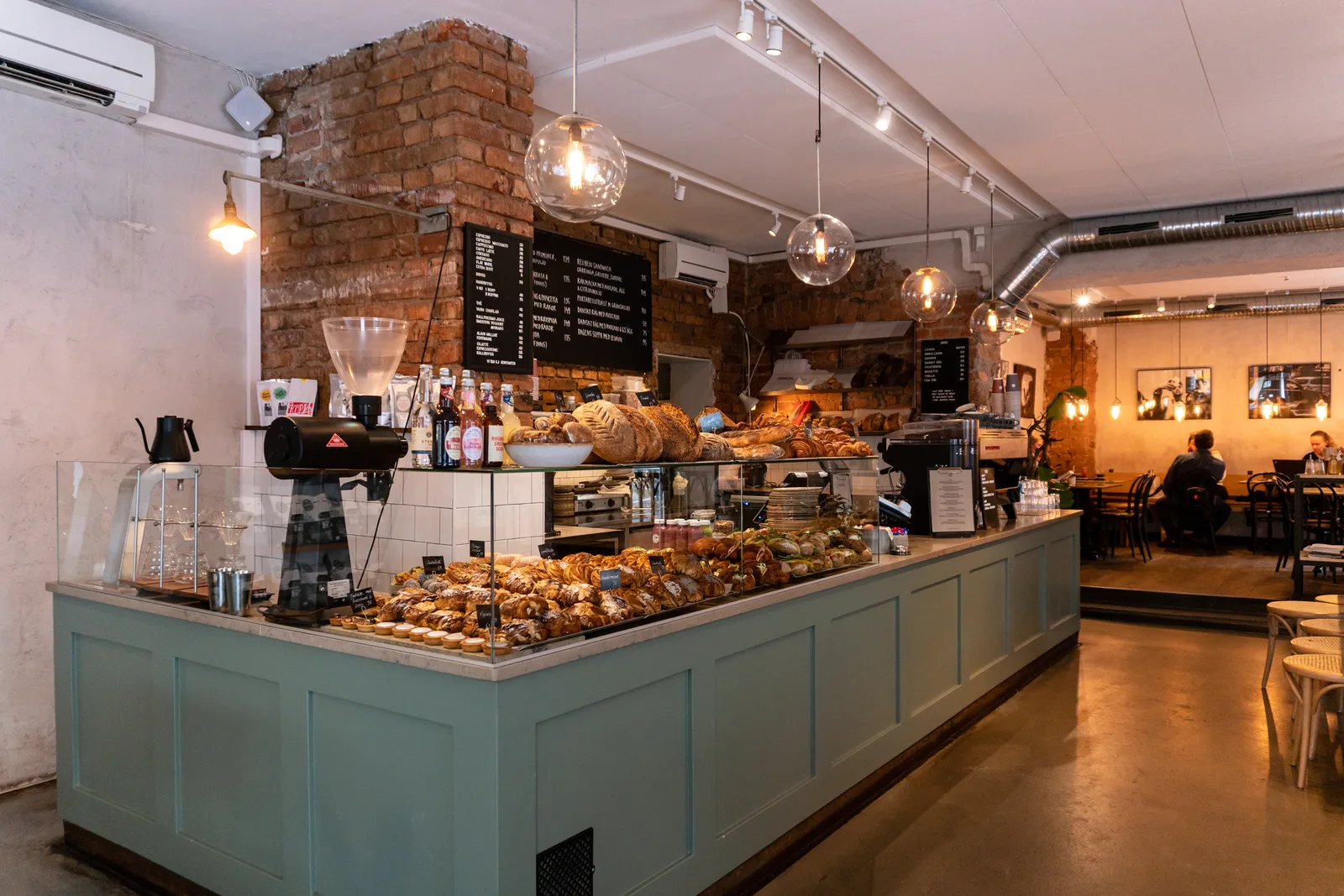 modern bakery café with pastries, pendant lights, and exposed brick walls., café pascal - södermalm, stockholm