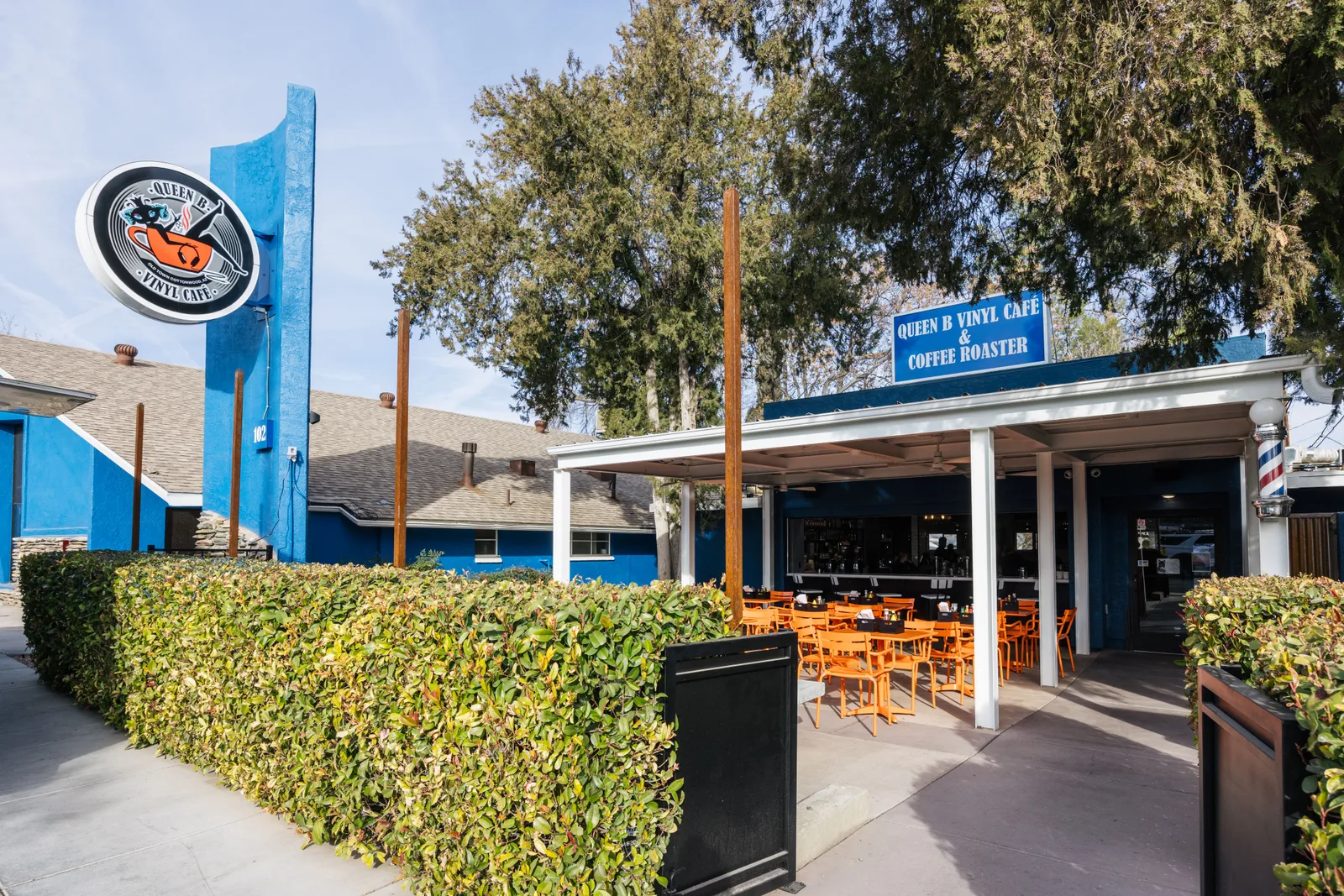 queen b vinyl cafe and coffee roaster storefront with blue signage and orange chairs., cafe puscifer, cottonwood