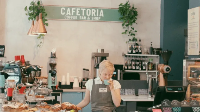 cafeteria coffee bar with barista, pastries, plants, and beverage shelves., cafetoria café & shop, helsinki