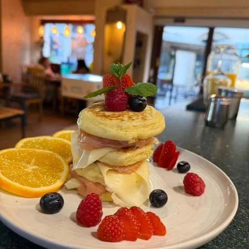 stacked pancakes with ham, cheese, berries, and orange slices on plate., caffè - pizzeria del 900 firenze, florence
