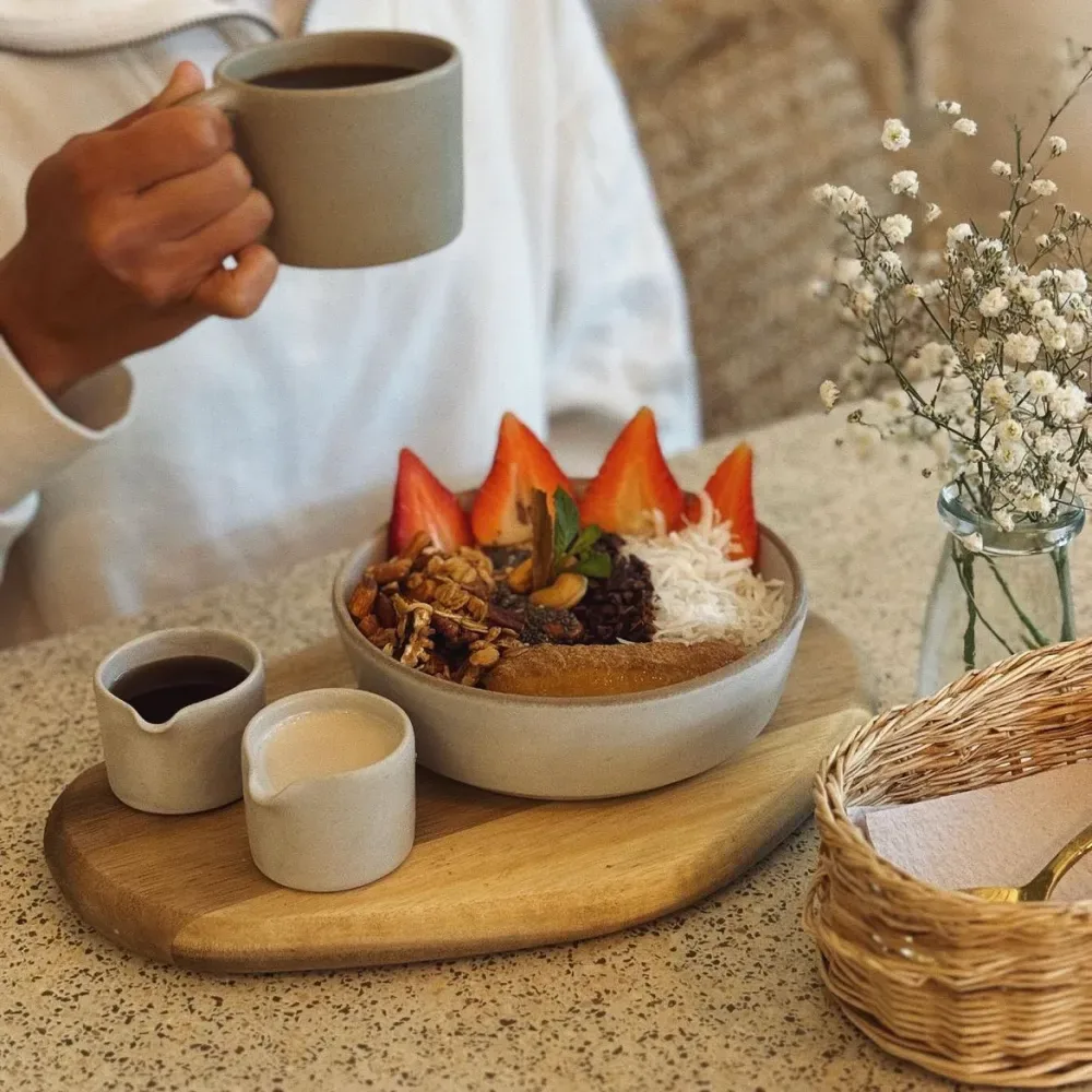 person holding mug above artfully plated dessert with strawberries and granola., caleta dolsa coffee, barranco