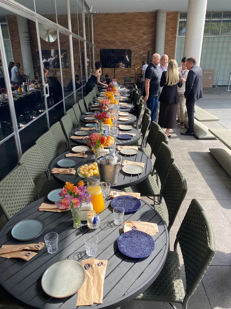 long outdoor dining table set with flowers, plates, and glassware for event., cantina do mam, rio de janeiro