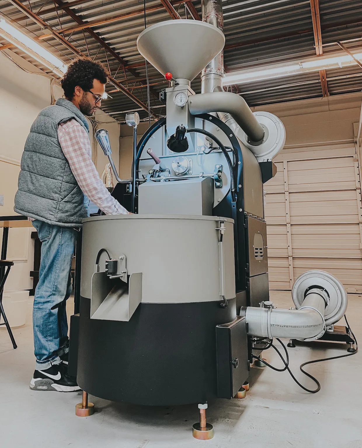 man operating large industrial coffee roasting machine in warehouse facility., canvas coffee roasters, newport news
