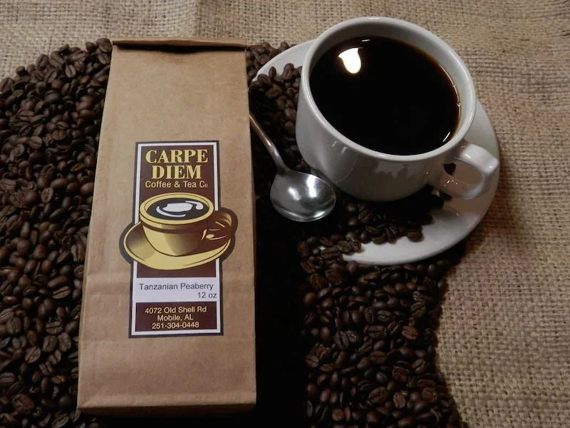 carpe diem coffee bag with tanzanian peaberry beside brewed black coffee cup., carpe diem coffee & tea company, alabama
