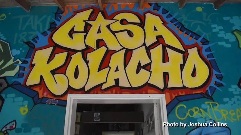 bright yellow "gasa kolacho" graffiti art above doorway on turquoise wall., casa kolacho, medellín