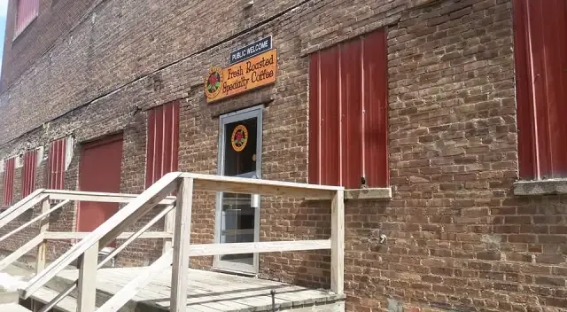 brick building with red doors, white ramp, and yellow signage overhead., caturra coffee roasting company, sioux city