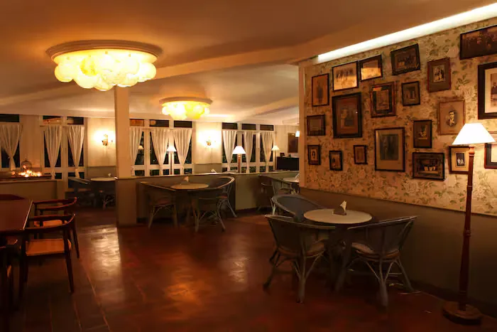 elegant interior with framed artwork, round tables, warm lighting, and vintage décor., chamiers cafe, chennai