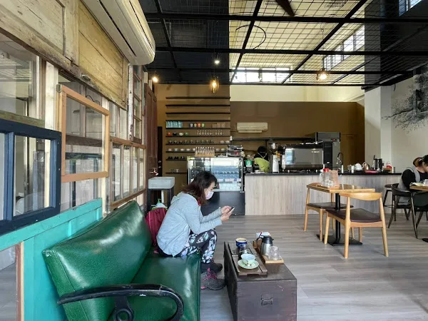 modern café interior with green seating, wooden tables, and customer ordering at counter., 獨咖啡（新莊旗艦店）, changping village