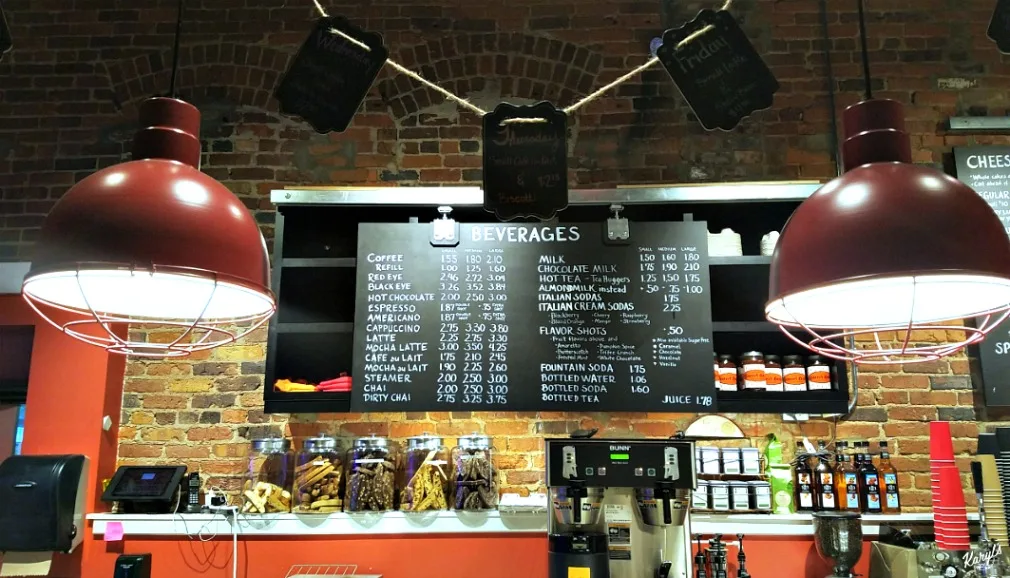 coffee shop counter with menu board, red pendant lamps, and beverage pricing displayed., cheesecakes by alex, greensboro