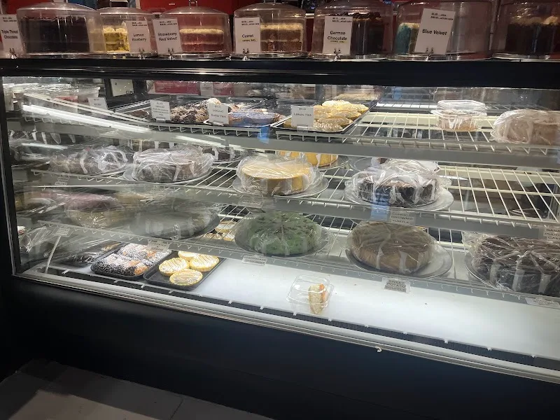bakery display case with assorted pastries, cakes, and baked goods on multiple shelves., cheesecakes by alex, greensboro