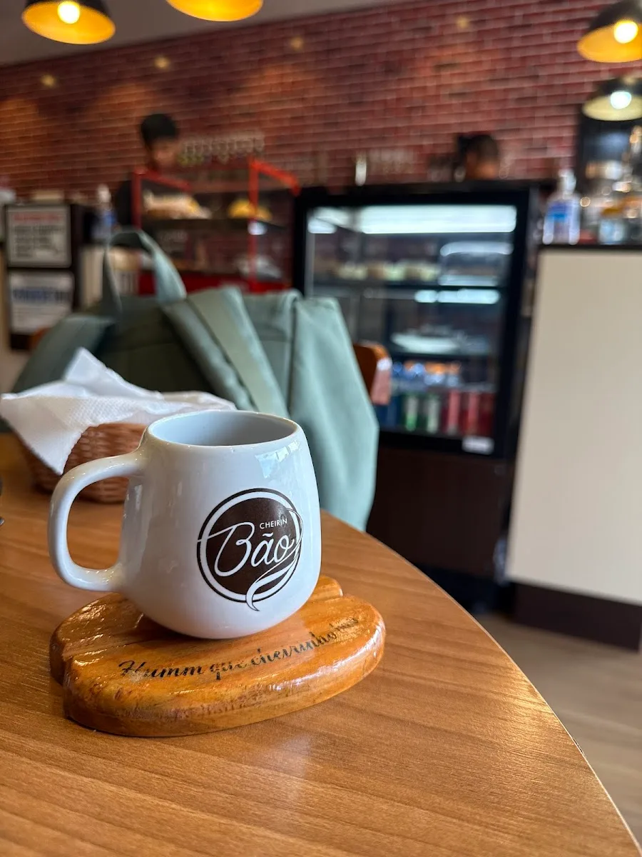 white mug with "baao" logo on wooden coaster in café interior with brick walls., cheirin bão 313 norte, brasília