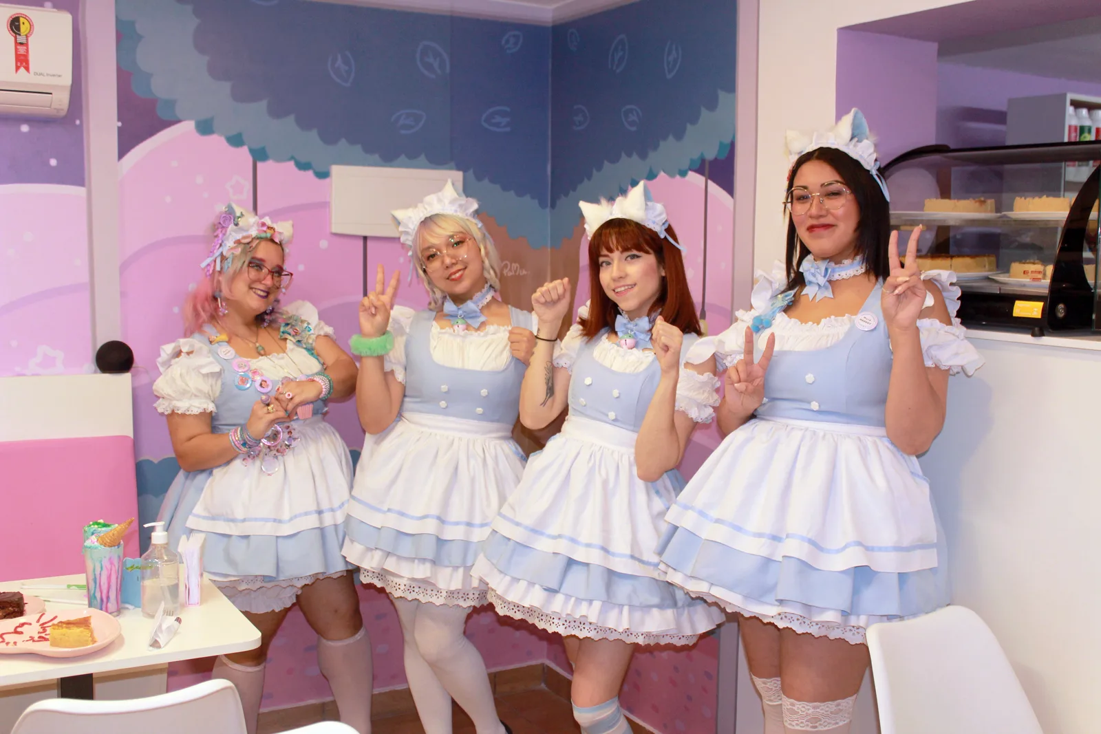 four people wearing matching pastel blue and white maid costumes in a pink-themed room., chest of wonders - maid café, são pa