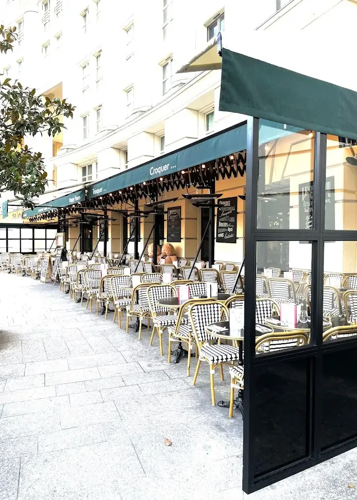 outdoor café terrace with striped chairs, dark green awning, and modern storefront., choubidou, paris