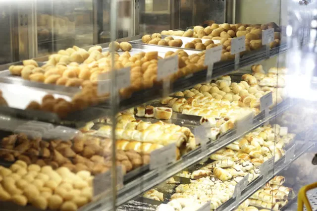 display case filled with various golden pastries and baked goods arranged in rows., cinco estrelas casa de pães asa sul: café