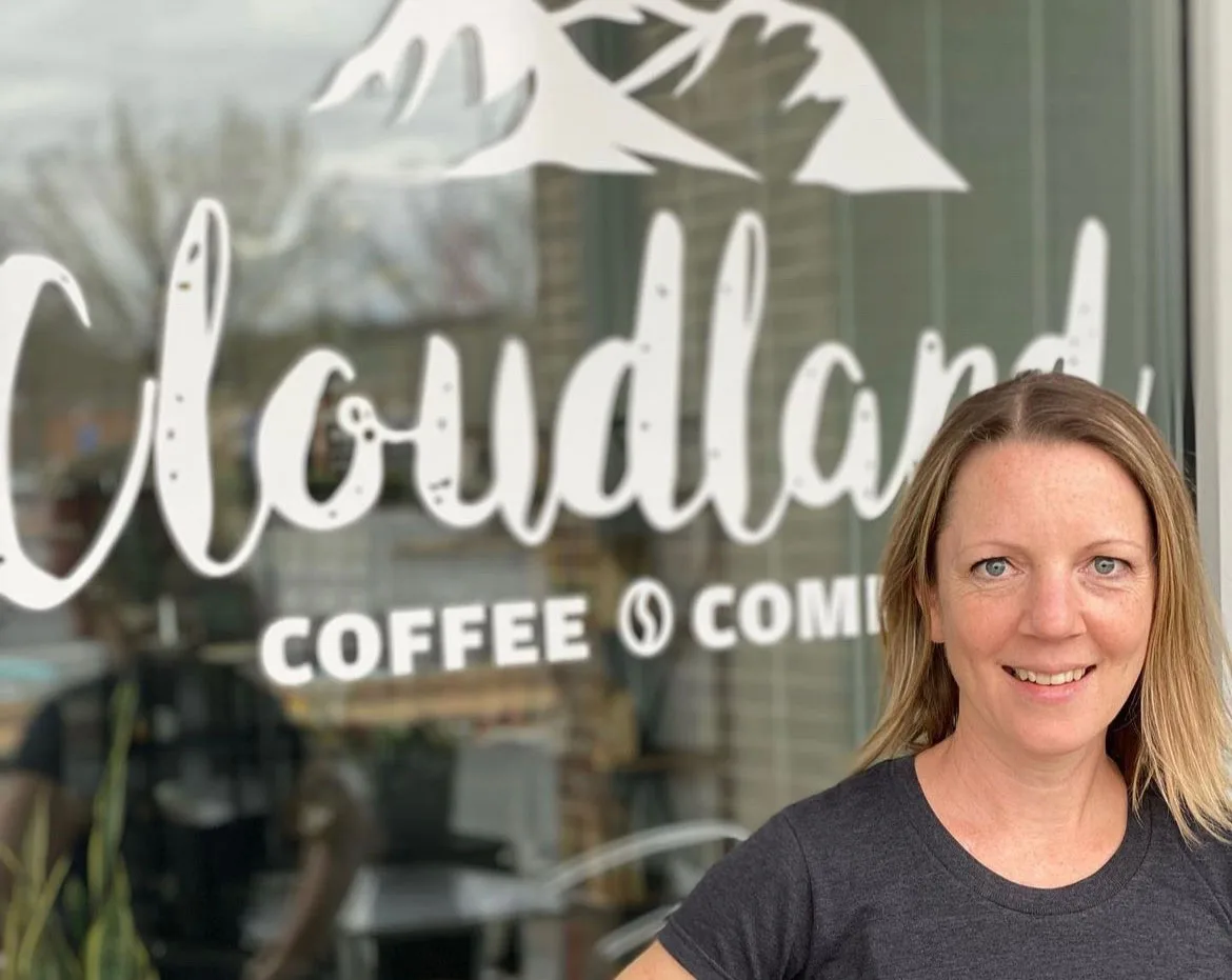 woman smiling in front of coffee shop window with decorative lettering., cloudland coffee company, atlanta