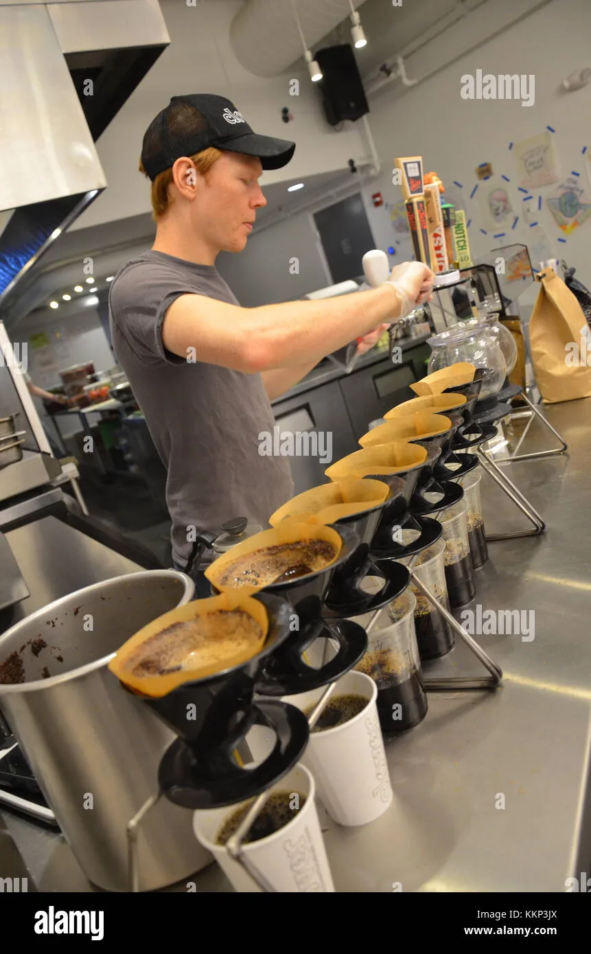 worker pouring coffee into multiple cups during tasting or cupping session., clover food lab, boston