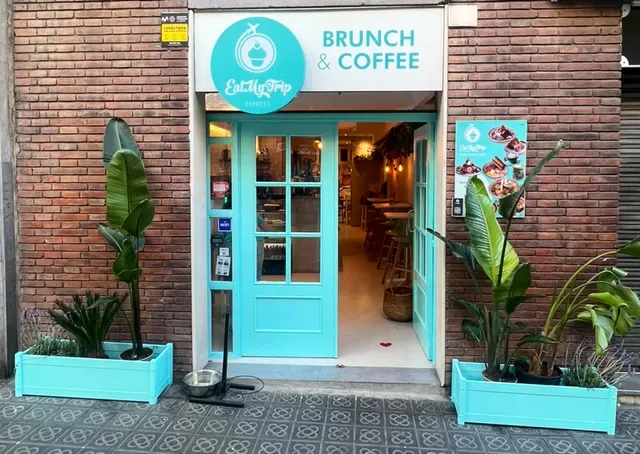 turquoise brunch and coffee shop storefront with potted plants flanking entrance door., coco social house | gràcia, barcelona