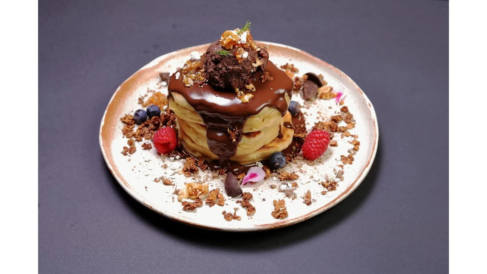 elegant chocolate dessert with pastry, berries, granola, and edible flowers on plate., coco social house - valència, valència