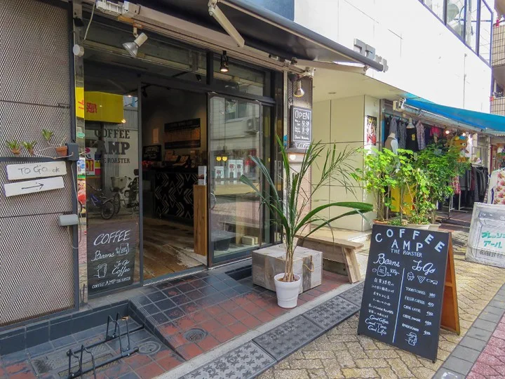 small japanese coffee shop storefront with plants and menu board on sidewalk., coffee amp the roaster, tokyo