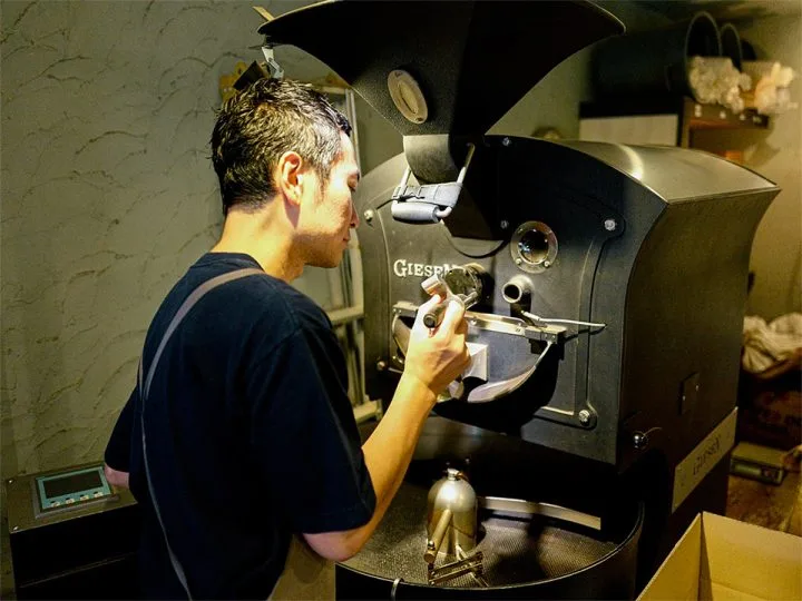 man operating industrial coffee roaster machine in professional roasting facility., coffee amp the roaster, tokyo