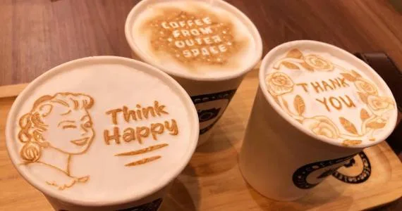 three white cups with latte art designs on wooden surface indoors., coffee selfie, são paulo