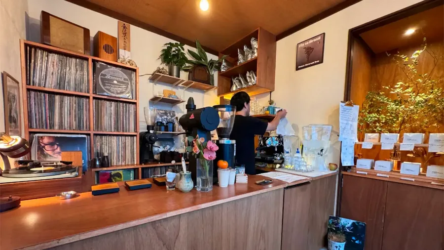 cozy vintage café interior with vinyl records, wooden shelves, and flower arrangement on counter., coffee swamp, tokyo