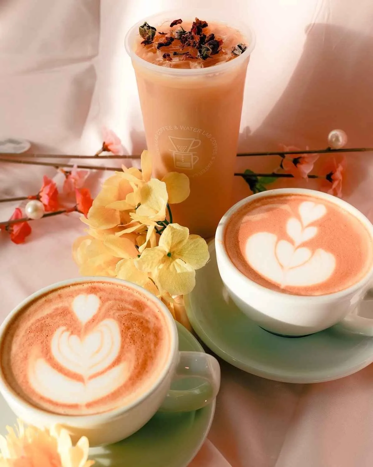 two heart latte arts and one iced peach beverage with flower garnish., coffee & water lab, san jose